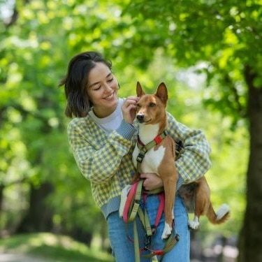 A woman holds a dog.